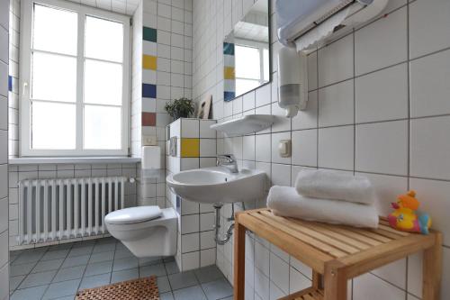 a white bathroom with a sink and a toilet at Kolping Hostel Trier im Warsberger Hof in Trier