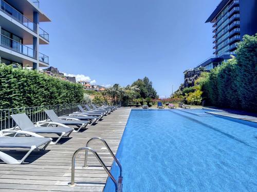 a swimming pool with chaise lounge chairs next to a building at Funchal Frui Vita by Atlantic Holiday in Funchal