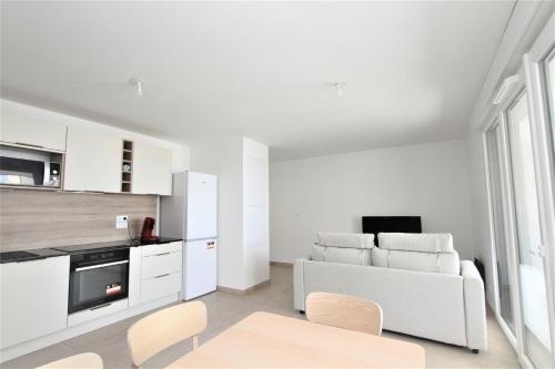 - un salon blanc avec un canapé et des fauteuils blancs dans l'établissement Appartement 2 chambres, vue mer et parking, à Canet