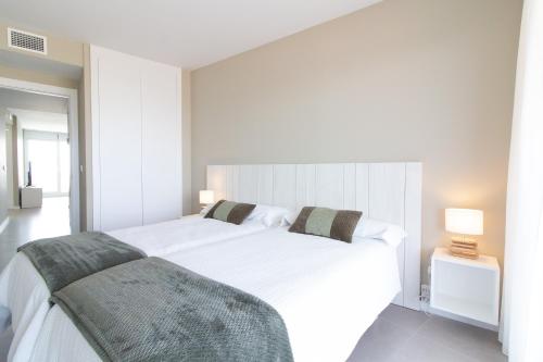1 dormitorio blanco con 1 cama blanca grande y 2 almohadas en Global Properties, Moderno apartamento con 2 terrazas y 3 habitaciones, en Canet de Berenguer