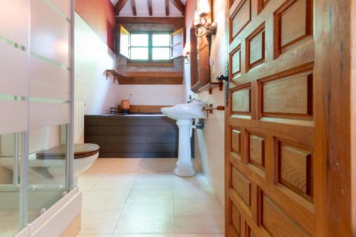 ein Bad mit einem WC, einem Waschbecken und einer Tür in der Unterkunft Secret Retreat by Fidalsa in Entrambasaguas