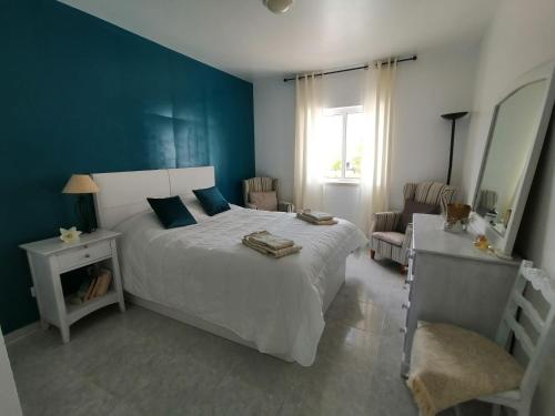 a bedroom with a white bed and a blue wall at Sao Rafael Beach Flat in Albufeira