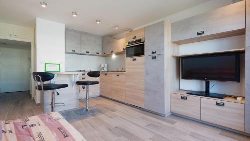 eine Küche mit einem großen TV und 2 Hockern in der Unterkunft Terrasses de l Espiguette 320 - Studio 2 pers in Le Grau-du-Roi