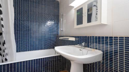 een blauw betegelde badkamer met een wastafel en een spiegel bij Terrasses de l Espiguette 320 - Studio 2 pers in Le Grau-du-Roi