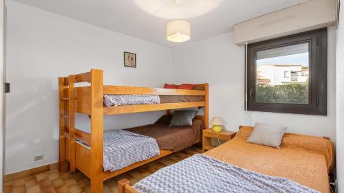une chambre avec deux lits superposés et une fenêtre dans l'établissement Port Lano 112 - Appt cosy - 7 Personnes, au Cap d'Agde