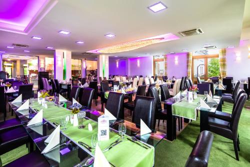 a banquet hall with green tables and black chairs at Hotel Vécsecity in Hernádvécse
