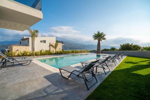 a swimming pool with chaise lounge chairs next to a house at Jarko Luxury Houses in Argoulidhés
