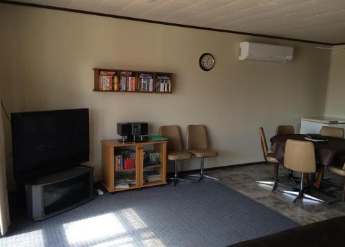 ein Wohnzimmer mit einem TV, einem Tisch und Stühlen in der Unterkunft All Decked Out in Edithburgh in Edithburgh