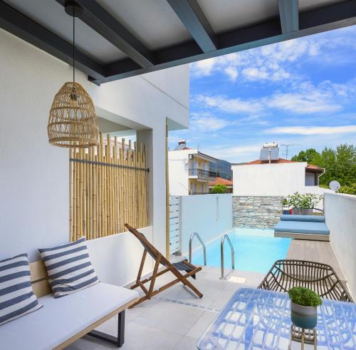 a patio with a couch and a table and a pool at Alea Suites -Adults Only and Kids 14 Plus in Asprovalta