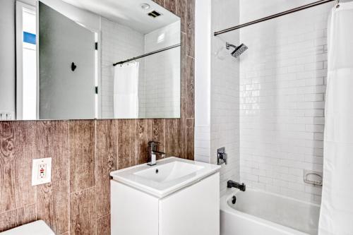 a bathroom with a sink and a tub and a mirror at Tribeca 1BR w Gym Doorman Roof deck NYC-54 in New York