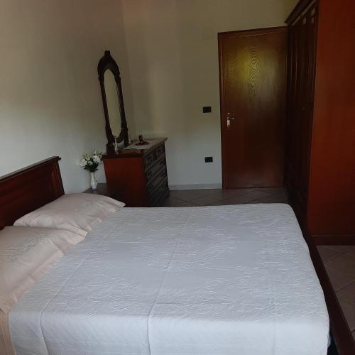 a bedroom with a white bed and a wooden door at Casa Zeno in Volterra