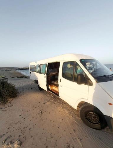 Gipsy Van Fuerteventura في بويرتو ديل روزاريو: سيارة فان بيضاء متوقفة على جانب طريق ترابي