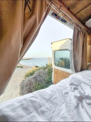 a bedroom with a bed and a view of the beach at Gipsy Van Fuerteventura in Puerto del Rosario