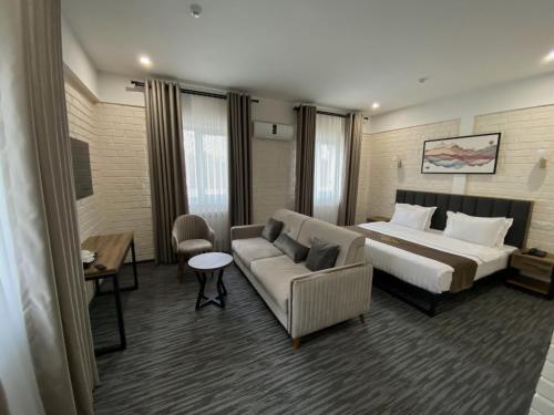 een hotelkamer met een bed en een bank bij Vatan Plaza in Tasjkent