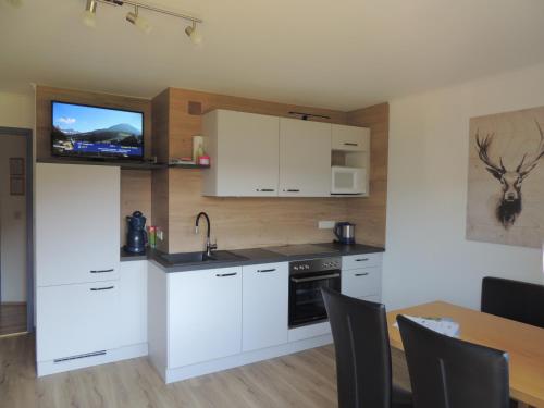 a kitchen with white cabinets and a television on the wall at Haus Bergfried in Filzmoos