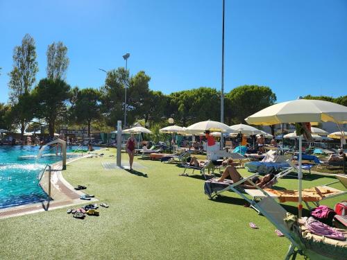 a group of people laying on the grass near a swimming pool at APPARTAMENTO PAMELA b&b in Grado