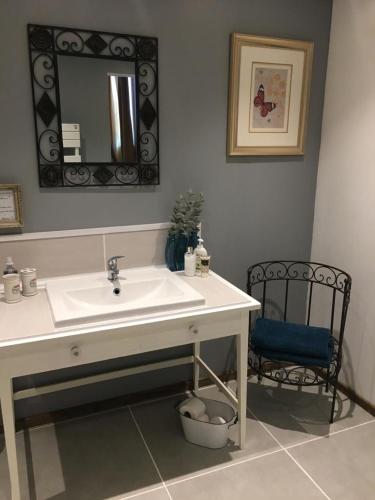 une salle de bain avec un lavabo, un miroir et une chaise dans l'établissement Bleu Lavande Chambre d’Hotes (B&B), à Madré