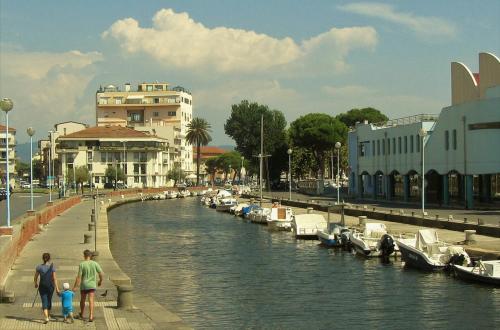 a group of people standing next to a river with boats at I Levrieri in Torre del Lago Puccini