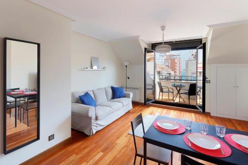 ein Wohnzimmer mit einem Tisch und einem Sofa in der Unterkunft Ático con terraza, vistas al mar y parking en playa de S Lorenzo in Gijón