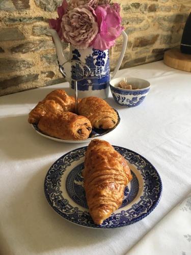 une table avec des assiettes de pâtisseries et un vase de fleurs dans l'établissement Bleu Lavande Chambre d’Hotes (B&B), à Madré