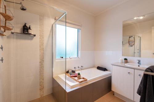 a bathroom with a tub and a sink and a shower at Sol Living Beach House in Brentwood