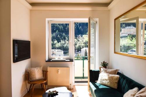 a living room with a green couch and two windows at Brand-new, central apartment w/ VIEWS in Bad Gastein