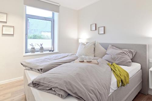 two beds in a white bedroom with a window at Op’n Diek in Fehmarn