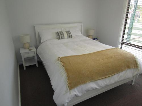 ein Schlafzimmer mit einem weißen Bett und einer gelben Decke darauf in der Unterkunft Hardwicke Haven in Brentwood