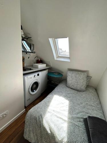 - une petite chambre avec un lit et un lave-linge dans l'établissement Amsterdam 11 - Saint-Lazare - Studio, à Paris