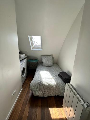 Cette petite chambre comprend un lit et un lave-linge. dans l'établissement Amsterdam 11 - Saint-Lazare - Studio, à Paris