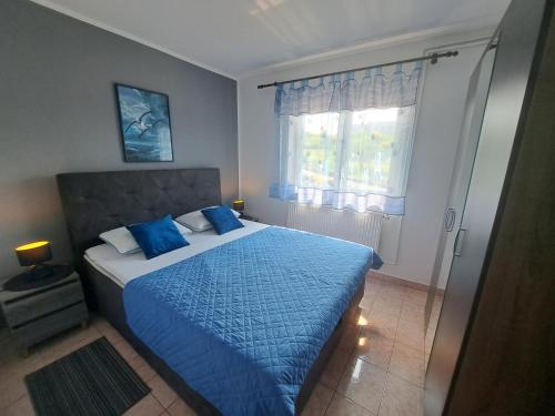 een slaapkamer met een bed met blauwe lakens en een raam bij Apartment Leo in Baška