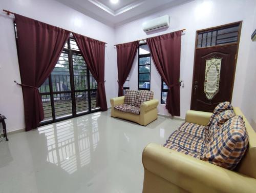 a living room with two chairs and windows at NikNa Homestay Batu Rakit - WIFI in Kampong Ru Tujoh