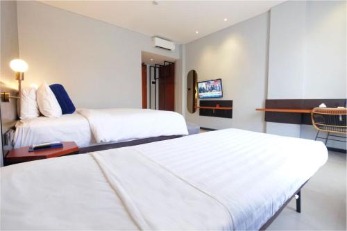 a hotel room with two beds and a television at Hotel Youstay Semarang by Sinergi in Kalibanteng-lor