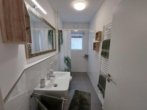 a white bathroom with a sink and a mirror at Gemütliche Familienwohnung in der Nähe des Nordparks und des Norparkcenters! in Bielefeld