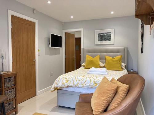 sypialnia z łóżkiem z żółtymi poduszkami i kanapą w obiekcie Malkin Wood Studio - 15 min walk to Holmfirth centre w mieście Holmfirth