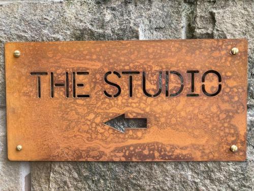 a sign that says the studio on a stone wall at Malkin Wood Studio - 15 min walk to Holmfirth centre in Holmfirth