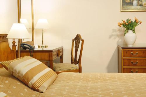 a bedroom with a bed with a chair and a desk at Hotel Kolonada in Karlovy Vary