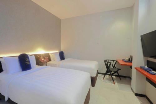 a hotel room with two beds and a television at Hotel Youstay Semarang by Sinergi in Kalibanteng-lor