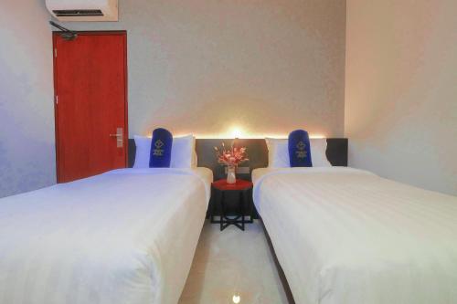 a room with two beds and a red door at Hotel Youstay Semarang by Sinergi in Kalibanteng-lor
