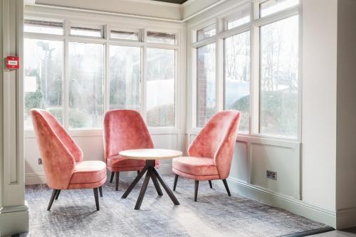 two chairs and a table in a room with windows at Holiday Inn Reading West by IHG in Reading