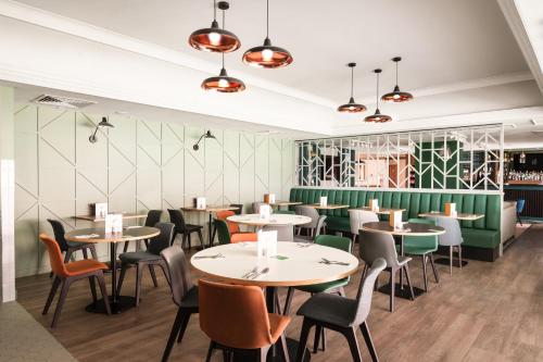 a restaurant with tables and chairs and a green wall at Holiday Inn Reading West, an IHG Hotel in Reading