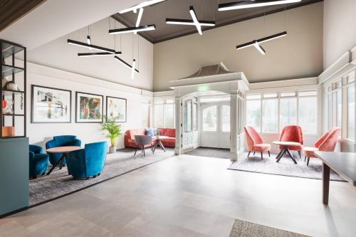 a living room with chairs and tables and windows at Holiday Inn Reading West by IHG in Reading