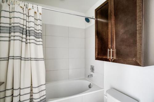 a bathroom with a tub and a shower curtain at Downtown 1br w gym deck wd nr 6th St bars ATX-21 in Austin