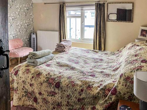 a bedroom with a bed with a blanket and a window at Star Yard in Tenbury