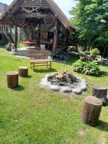 a park with a fire pit and a bench and logs at Adamowo in Uherce Mineralne