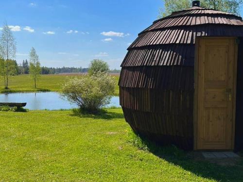 a large wooden hut with a door next to a pond at Mežagaiļu idiļļa in Rēzekne