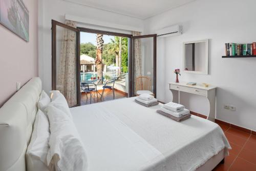 a bedroom with a white bed and a balcony at Villa Lianolia in Perítheia