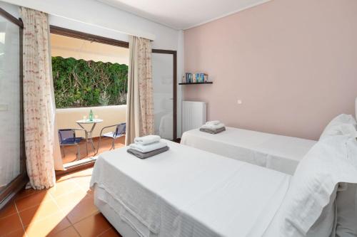 a bedroom with two beds and a balcony with a table at Villa Lianolia in Perítheia