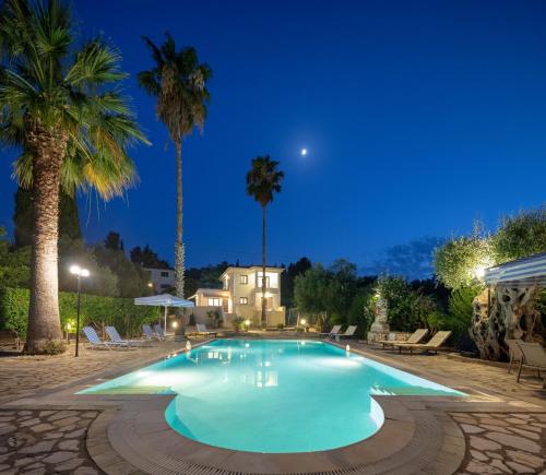 a swimming pool at night with palm trees at Villa Lianolia in Perítheia