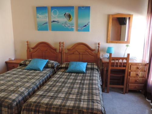 a bedroom with two beds and a desk and a table at Hostal Sali in Pelabravo